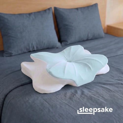 Sleepsake butterfly pillow on a bed with gray bedding and pillows.